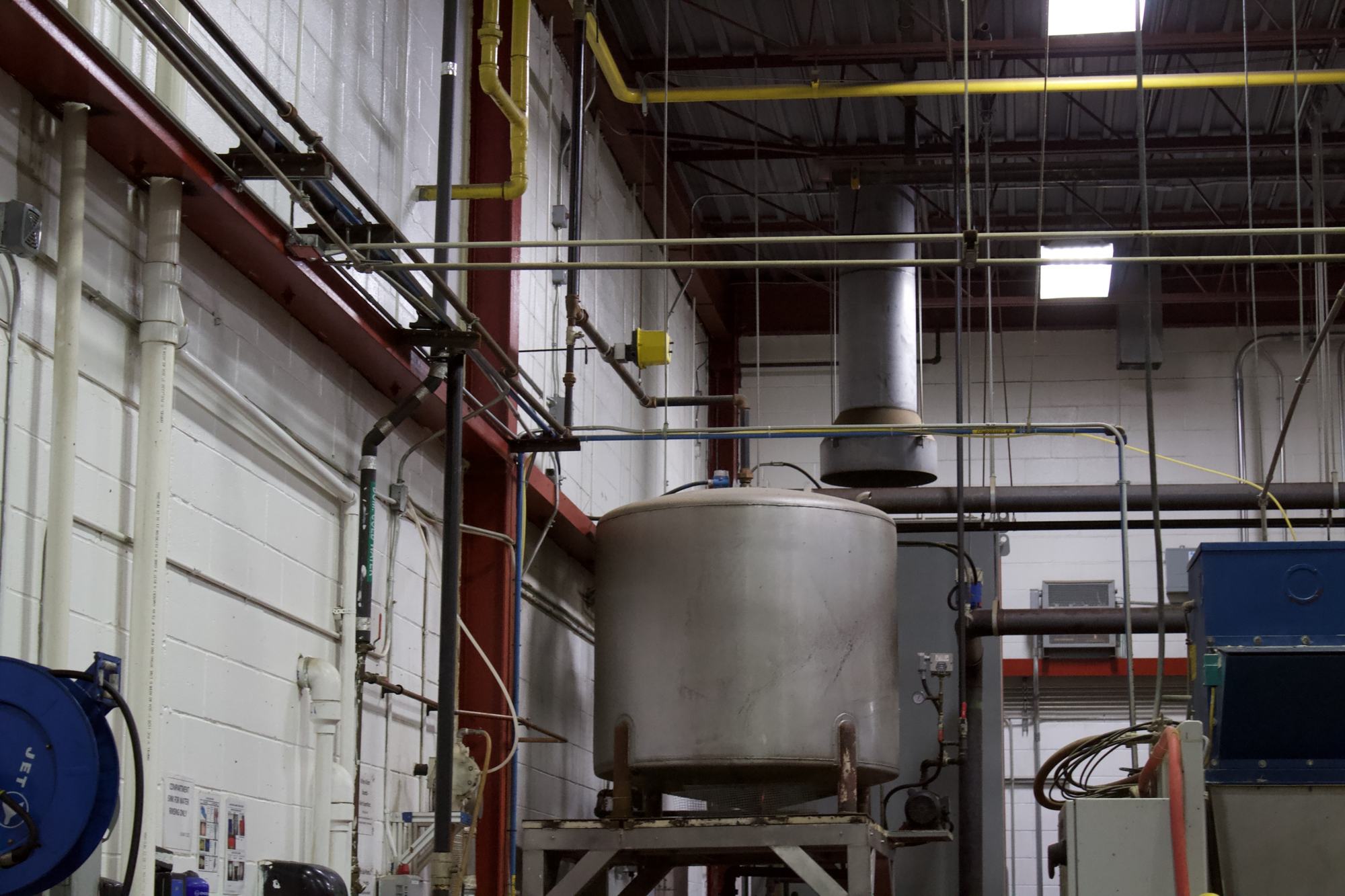 Stainless kettle and gas-fired equipment inside an industrial plant