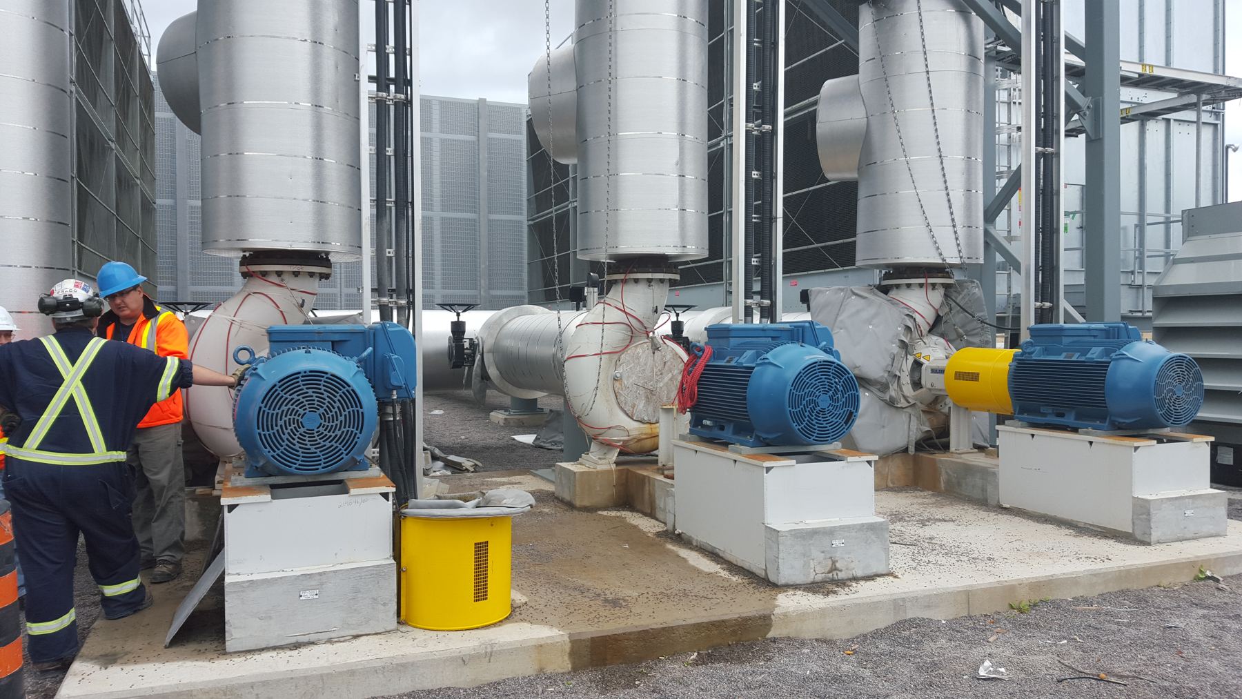 Crew working beside large pump motors at an outdoor plant